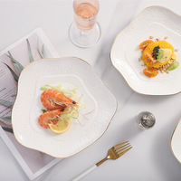 Assiette en céramique de luxe à bord doré avec surface texturée en relief, forme carrée irrégulière pour la restauration fine et les événements