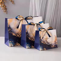 Sac cadeau en papier marbré bleu de luxe personnalisé avec poignée en ruban pour l'emballage de vente au détail