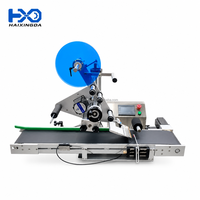 Machine d'étiquetage automatique industrielle pour surfaces planes supérieures de boîtes, cartons et sachets avec applicateur d'autocollants adhésifs