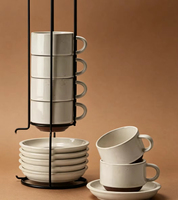 Ensemble élégant et tendance de tasses et soucoupes en céramique blanche, avec support métallique pour l'affichage, idéal pour la table à manger domestique et les scénarios de service du café et du thé.