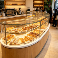 Vitrine de boulangerie de luxe haut de gamme avec cadre en métal doré, verre incurvé, éclairage LED, durable et multifonctionnelle, comptoir de vente au détail