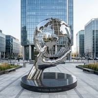 Grande sculpture de globe terrestre creux en acier inoxydable poli miroir, en forme de main tenant un globe, pour l'aménagement paysager des places universitaires