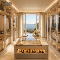 Dressing de luxe style Riviera française avec portes vitrées en treillis métallique et îlot central champagne pour suite principale de villa