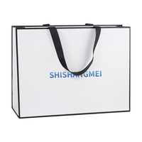 Sac cadeau en papier couché blanc avec impression de logo dégradé bleu et poignée noire côtelée effet ombré pour emballage de marque de luxe