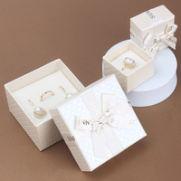Caja de regalo de joyería de Navidad pequeña directa de fábrica Paquete de joyería 2023 con nodo Debossed logo cinta Lazo y esponja