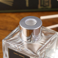 Diffuseur de parfum d'ambiance en verre carré transparent avec logo personnalisé, bouchon argenté, boule de rotin naturel et fleur de Sola blanche – Décoration et cadeau pour la maison