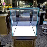 Présentoir sur pied en verre recyclable et écologique avec finition miroir personnalisée, éclairage LED et logo sur mesure pour bijouterie, horlogerie et showroom de marques.