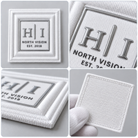 Étiquettes personnalisées en coton TPU avec logo 3D en relief, toucher doux, pour vêtements, streetwear et accessoires.