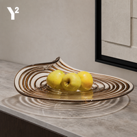 Luxueuze gedraaide spiraalvormige glazen schaal met amberkleurige tint voor fruitpresentatie in de woonkamer, op de salontafel of dressoir.
