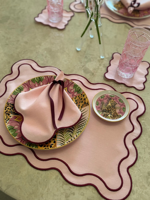 Set aus rosa Tischsets mit gewelltem Rand und burgunderroten Stoffservietten und Untersetzer, elegante Tischdekoration, kokettes Essensset