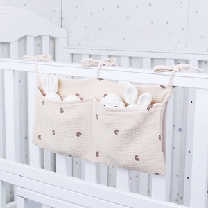 Bestseller Baumwoll-Musselin Babybett-Organizer für Neugeborene und Kleinkinder, Hängetasche mit zwei Taschen für Windeln, Beißringe und Spielzeug - Product Image 1