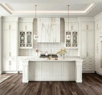 Armoire de cuisine sur mesure de luxe blanche à panneaux surélevés avec porte en verre décorative, quincaillerie dorée, grand îlot de cuisine pour la rénovation de la maison