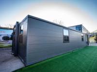 Maison conteneur modulaire extensible et amovible en panneaux sandwich gris, avec grandes fenêtres, pour retraite en montagne et usage hôtelier