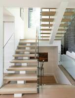 Escalier flottant de luxe avec poutre centrale en acier et garde-corps entièrement en verre pour duplex