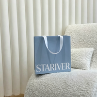 Sac cadeau en papier bleu poussière mat avec ruban en satin blanc et poignée à nœud, logo personnalisé en serif, sac de luxe pour boutique de parfums