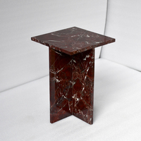 Table basse élégante en marbre scandinave bordeaux, sculpturale avec cadre en X, accent en pierre rouge profond, mobilier haut de gamme pour salon