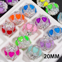Strass en forme de cœur de couleur fluorescente, associés à un pendentif en métal argenté en forme de fleur et à une chaîne de perles demi-perles.
