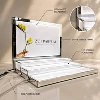 Présentoir à parfums moderne de luxe en acrylique à LED multi-niveaux, cadre en métal argenté, panneau arrière personnalisé à motif floral