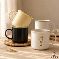Mug à café en céramique noir mat avec bordure dorée et lettrage imprimé, corps large et rond, poignée en forme de C, idéal pour le bureau au quotidien