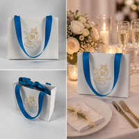 Sac en papier personnalisé avec emblème floral mat ivoire estampé à chaud or, avec poignée en ruban de satin bleu, pour cadeaux cosmétiques