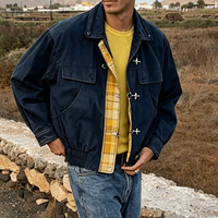 Blouson bomber Ouna personnalisé en tissu sergé délavé, avec empiècements à carreaux jaunes, style vintage pompier, et fermeture à bouton et mousqueton.
