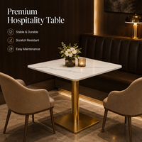 Table et chaises de restaurant, plateau carré en pierre frittée avec base cylindrique dorée et fauteuils beiges à accoudoirs en forme de baril pour café-bar