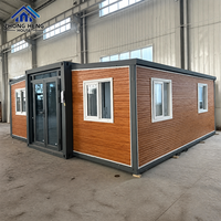 Maison conteneur extensible à double aile moderne avec entrée centrale en verre et multiples fenêtres pour l'habitation familiale