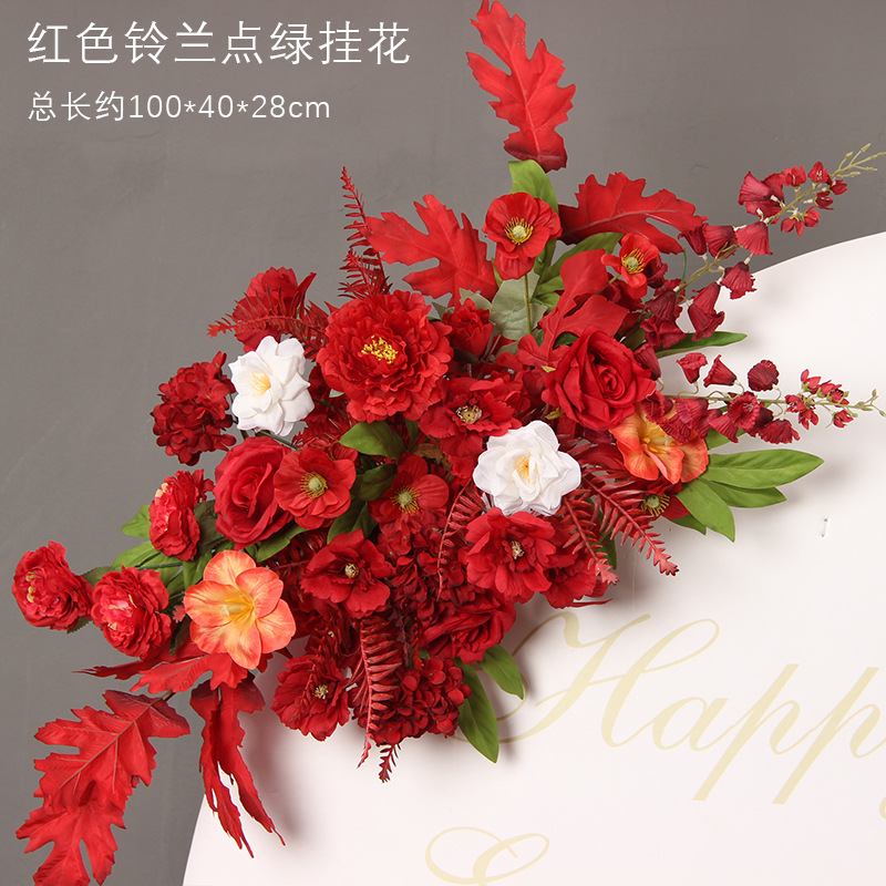 Muguet rouge pointant parmi des fleurs suspendues vertes.