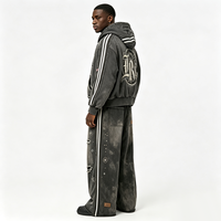 Ensemble de survêtement streetwear délavé avec sweat à capuche zippé et pantalon large, orné de patchs lettres gothiques Kornit DTG et rivets déchirés