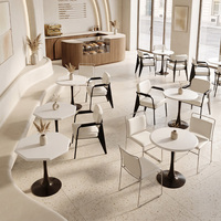Tables blanches de style minimaliste et chaises rembourrées douces, mobilier commercial pour pâtisserie et café