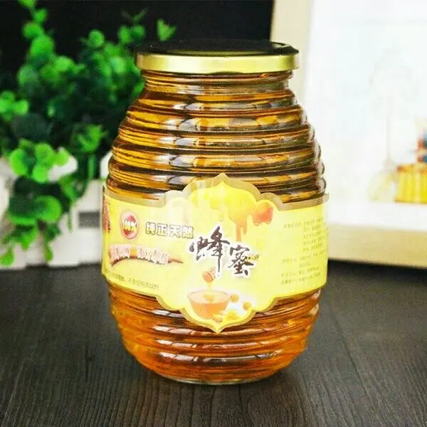 La fabbrica ha prodotto il barattolo di vetro del miele a forma di alveare/favo di dimensioni differenti all'ingrosso
