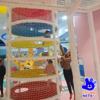 Structure de grimpette intérieure multi-niveaux en filet blanc avec poteaux rembourrés et plateformes colorées – Équipement commercial pour centre de jeux pour enfants