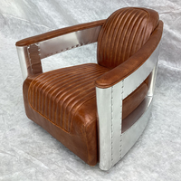 Fauteuil club pivotant en cuir style aviateur, avec accoudoirs en aluminium, pour un intérieur rétro américain.