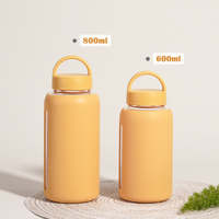 Bouteille d'eau portable en verre avec manchon en silicone antidérapant de 600 ml, double couvercle, design moderne, réutilisable, nouveauté pour l'extérieur, vente en gros