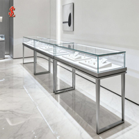 Vitrine de présentation de bijoux en verre avec cadre métallique gris et base cannelée, type îlot, pour magasin de détail, boutique, salle d'exposition, kiosque de centre commercial