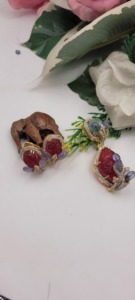 Les boucles d'oreilles sont ornées de pierres rouges sculptées et de pierres bleues serties dans un cadre doré, orné de petites pierres blanches. - Product Image 3