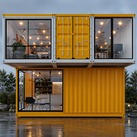 Maison en conteneur d'acier à deux étages, style cabane Apple, avec grandes fenêtres en verre jaunes, entièrement meublée, idéale pour séjour familial dans le jardin.