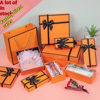Boîte cadeau en carton magnétique orange avec logo personnalisé, doublée d'éponge, structure rigide écologique, ruban à nœud, laminage mat