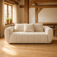 Canapé 3 places en tissu bouclé crème, capitonné, à profil bas et accoudoirs arrondis, pour maison rustique avec poutres en bois