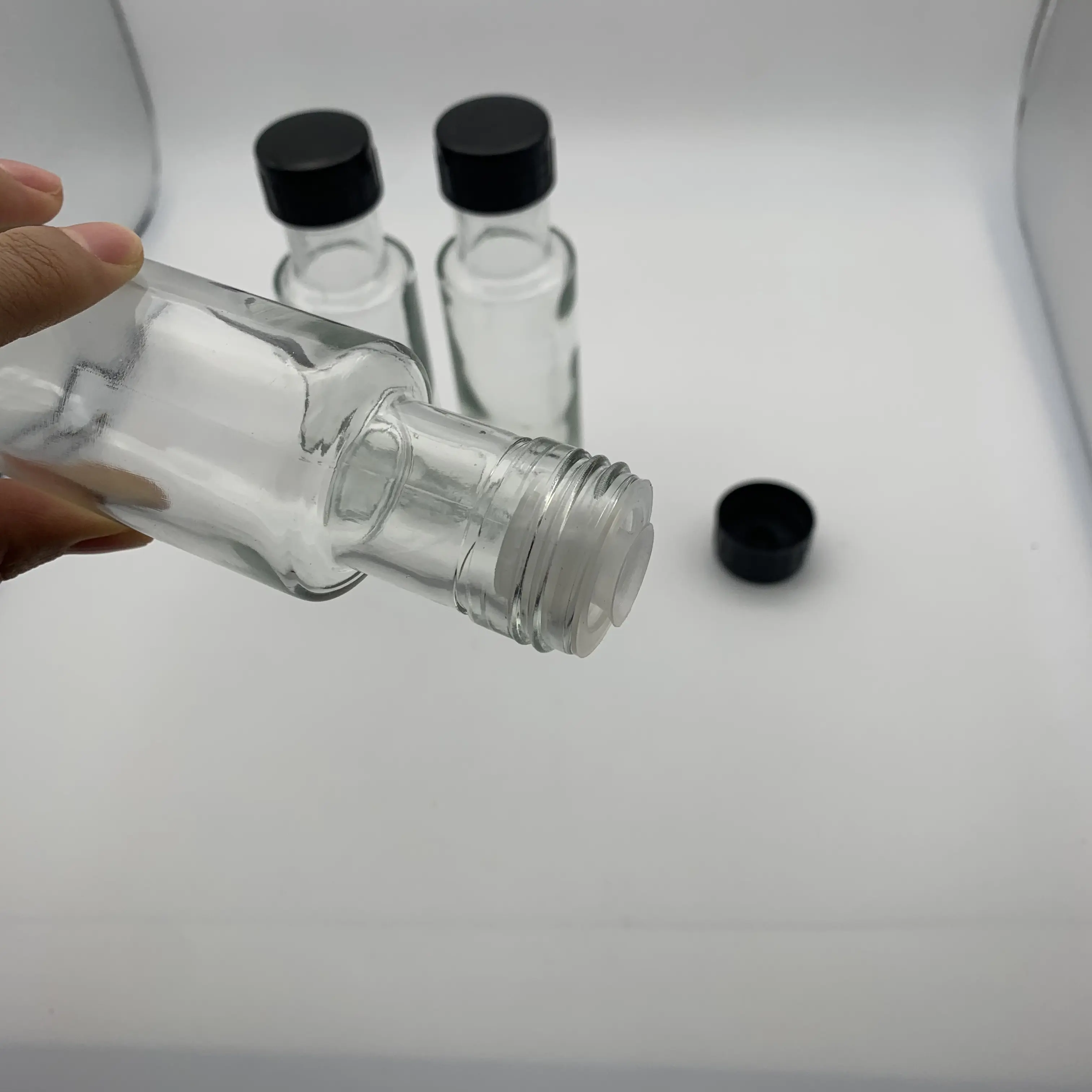 Wholesale 100ml Round Clear Flat Shoulder Glass Olive Oil Bottle With Plastic Screw Cap And Black Lid