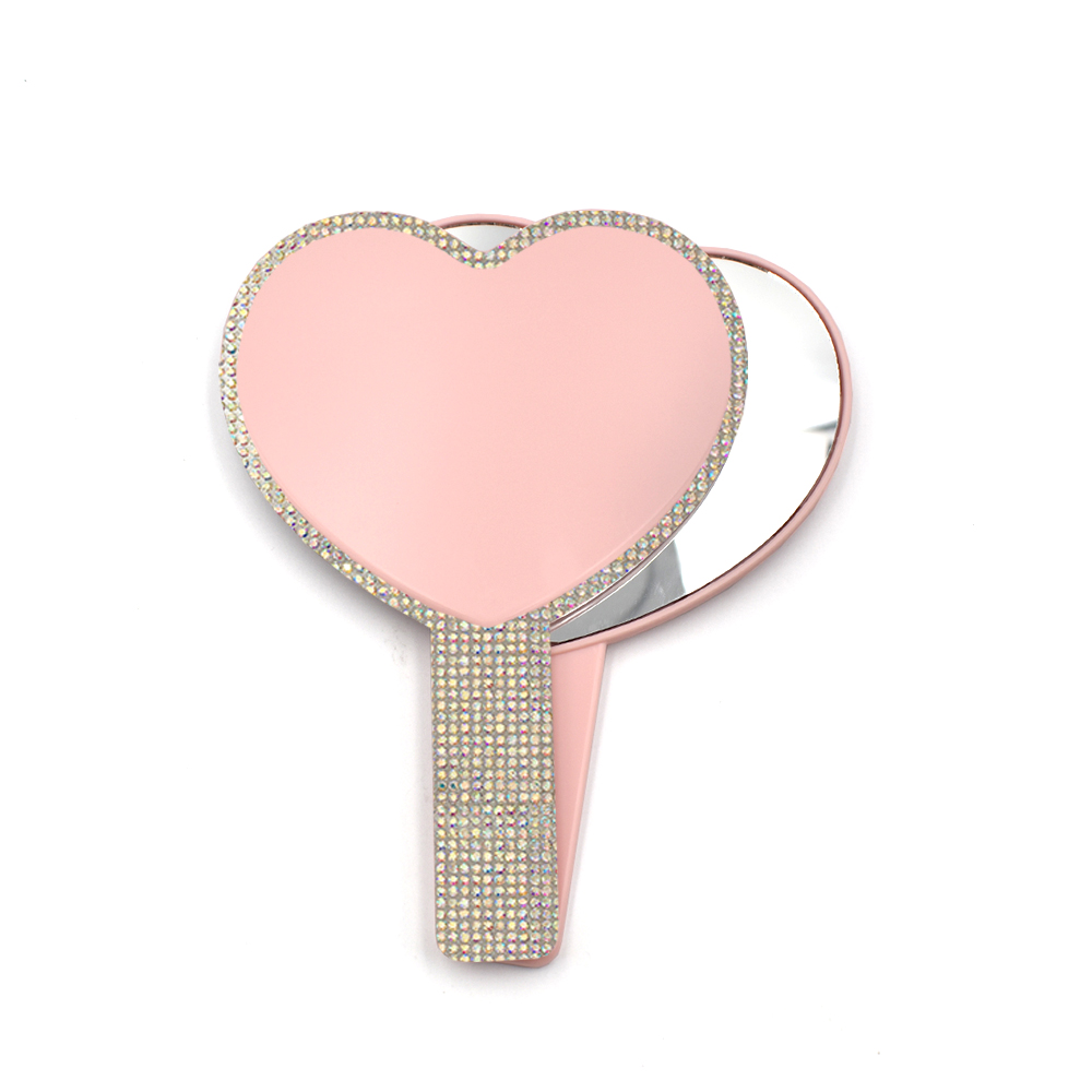 Espejo de mano con forma de corazón rosa y pedrería.