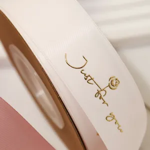 Rolo de fita de cetim personalizado com logotipo Lude 3D em relevo dourado com nome de marca estampado