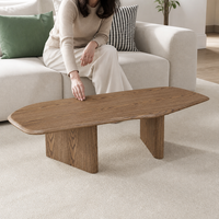 Table basse en bois grainé avec finition placage, silhouette allongée aux coins arrondis et pieds en panneaux pour mobilier de salon