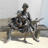 Statue en bronze sur mesure grandeur nature d'un garçon et d'une fille assis sur un banc en train de lire un livre