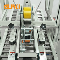 Scelleuse automatique de cartons GURKI GPC-50 à double colonne électrique avec fermeture par ruban adhésif et entraînement par engrenages pour l'emballage chimique