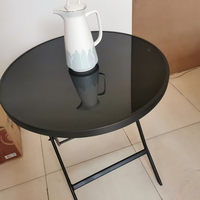 Table ronde pliante en verre trempé avec structure en métal noir, idéale pour les jardins extérieurs, les plages et les terrasses de restaurants