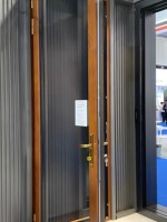 Una puerta abatible de madera maciza francesa moderna con un marco de aleación de aluminio y una puerta de vidrio exterior, delineando un ambiente cálido en el hogar