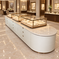 Comptoir de présentation de bijoux long avec plusieurs vitrines en verre, extrémités arrondies, tiroirs de rangement blanc crème pour les bijouteries de luxe