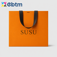 Sacs cadeaux en papier orange de luxe personnalisés en gros avec poignées en ruban noir pour l'emballage de détail
