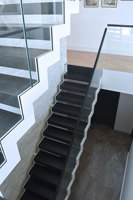 Escalier en zigzag noir avec marches en bois et balustrade en verre